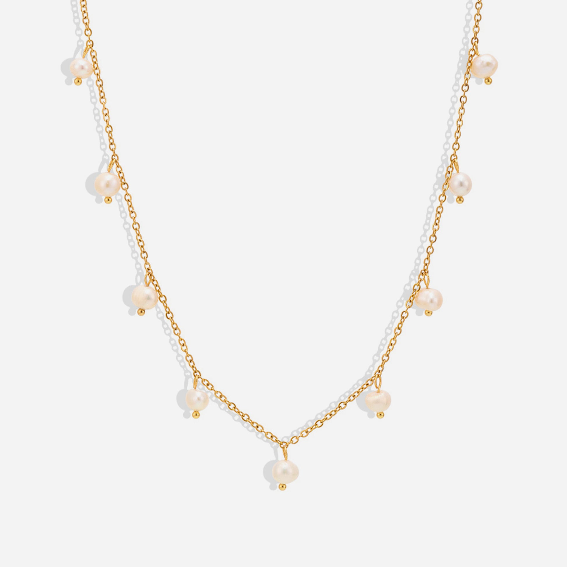 A gold-colored choker necklace featuring stations with freshwater pearls, presented against a white background.