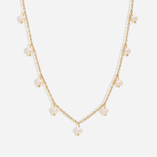 A gold-colored choker necklace featuring stations with freshwater pearls, presented against a white background.