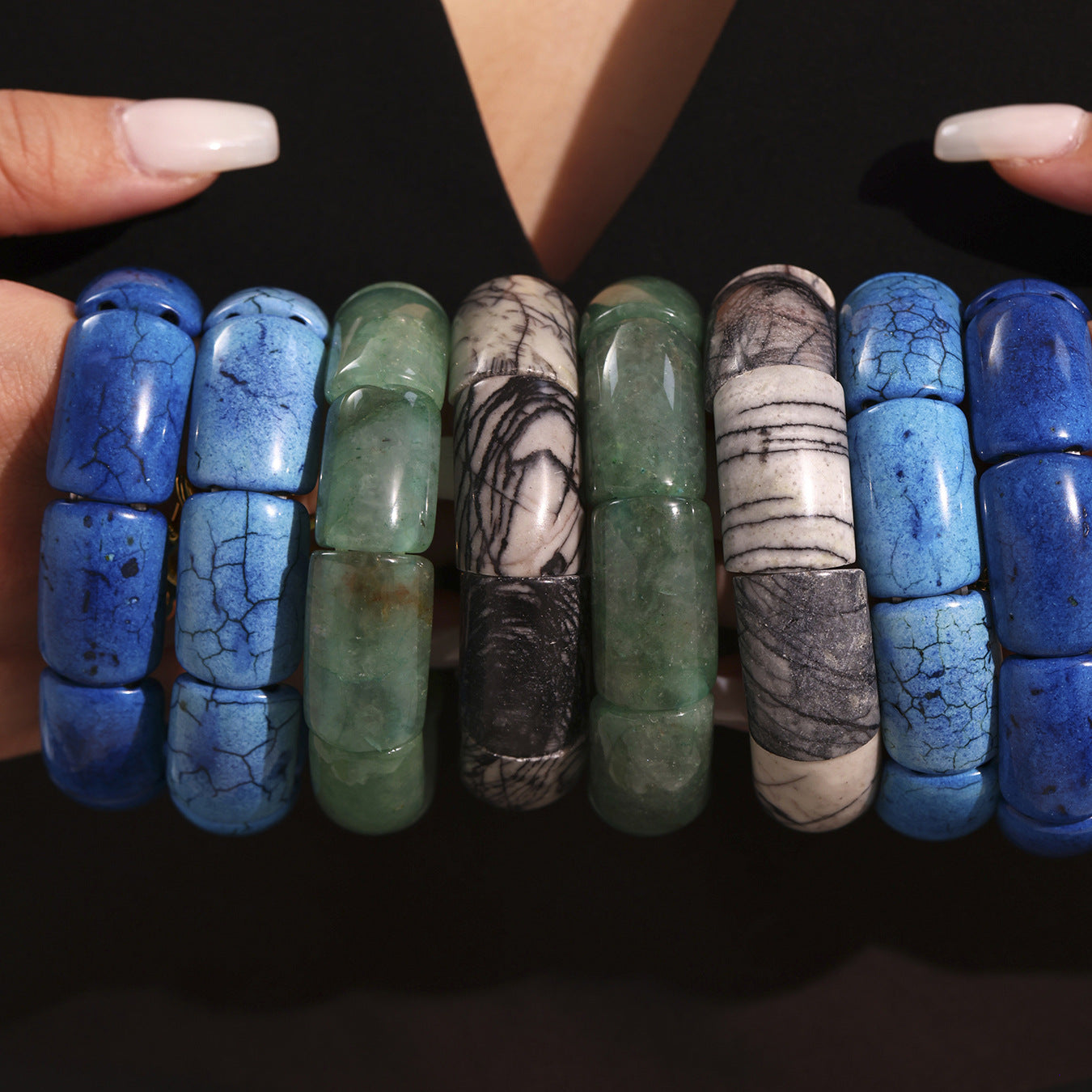 Hand holding beaded gemstone tennis bracelets – blue and green stones with stretch fit