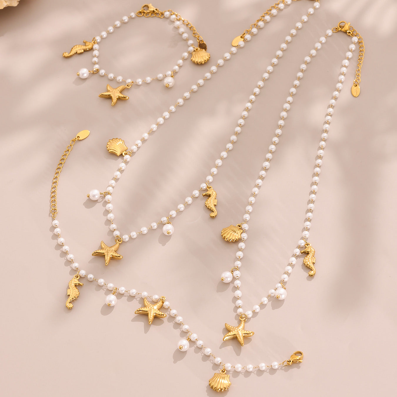 Pearl necklace with gold sea-themed charms on a beige background