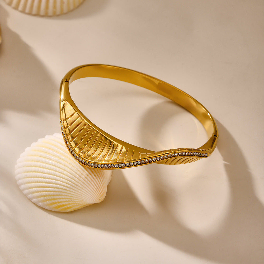 Gold bracelet with leaf design on a beige background