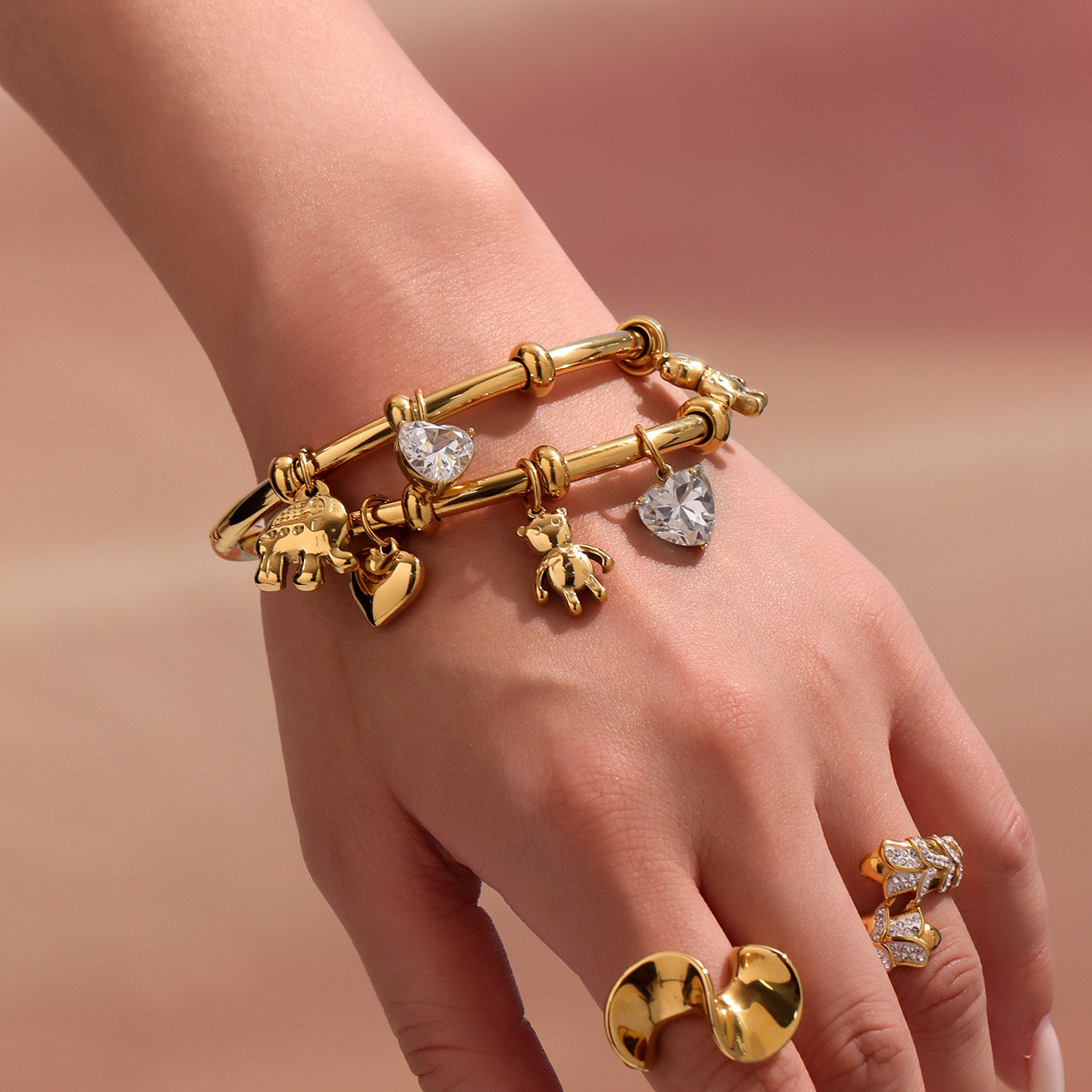 Gold tennis-style charm bracelet on hand with minimalist neutral background