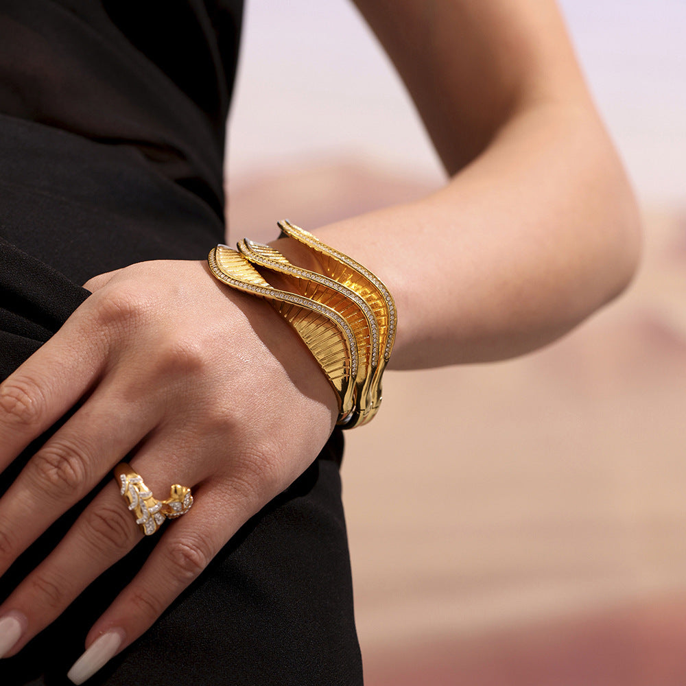 Gold bracelet and ring on a person's wrist with a blurred background