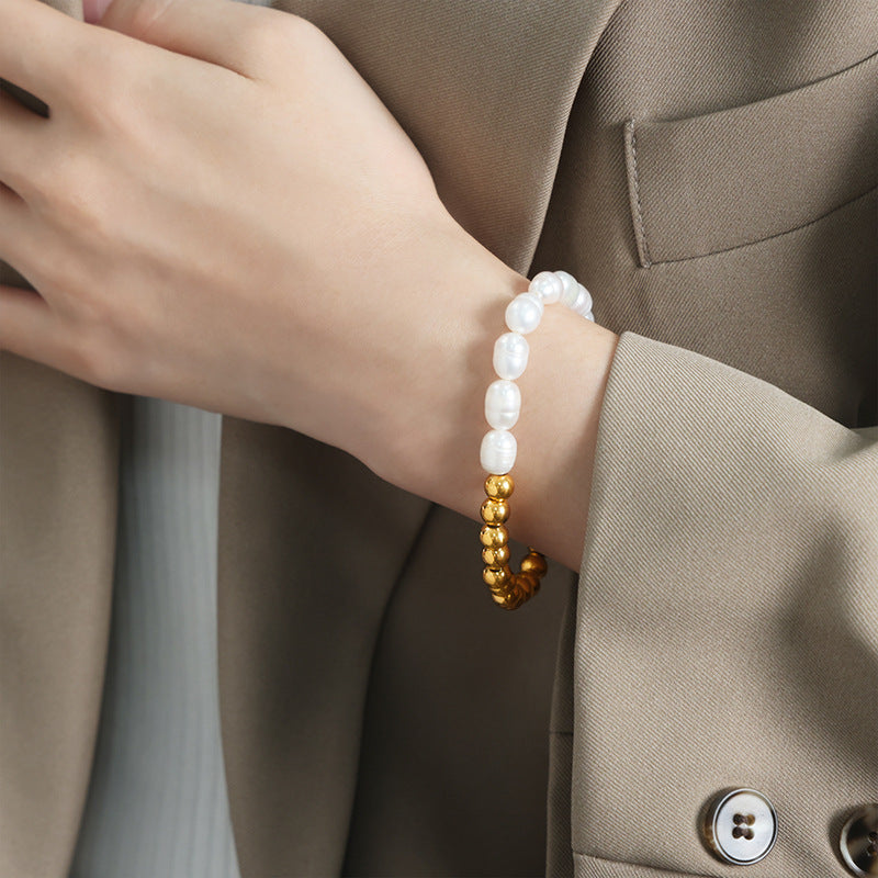 Close-up of handmade pearl bracelet on model’s wrist wearing green suit