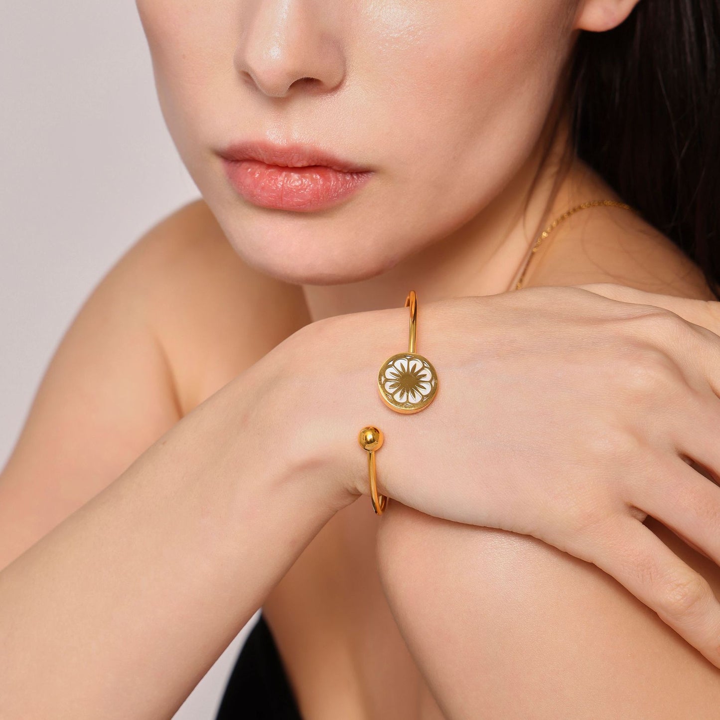 Detailed close-up of gold bracelets and necklace on woman with neutral background