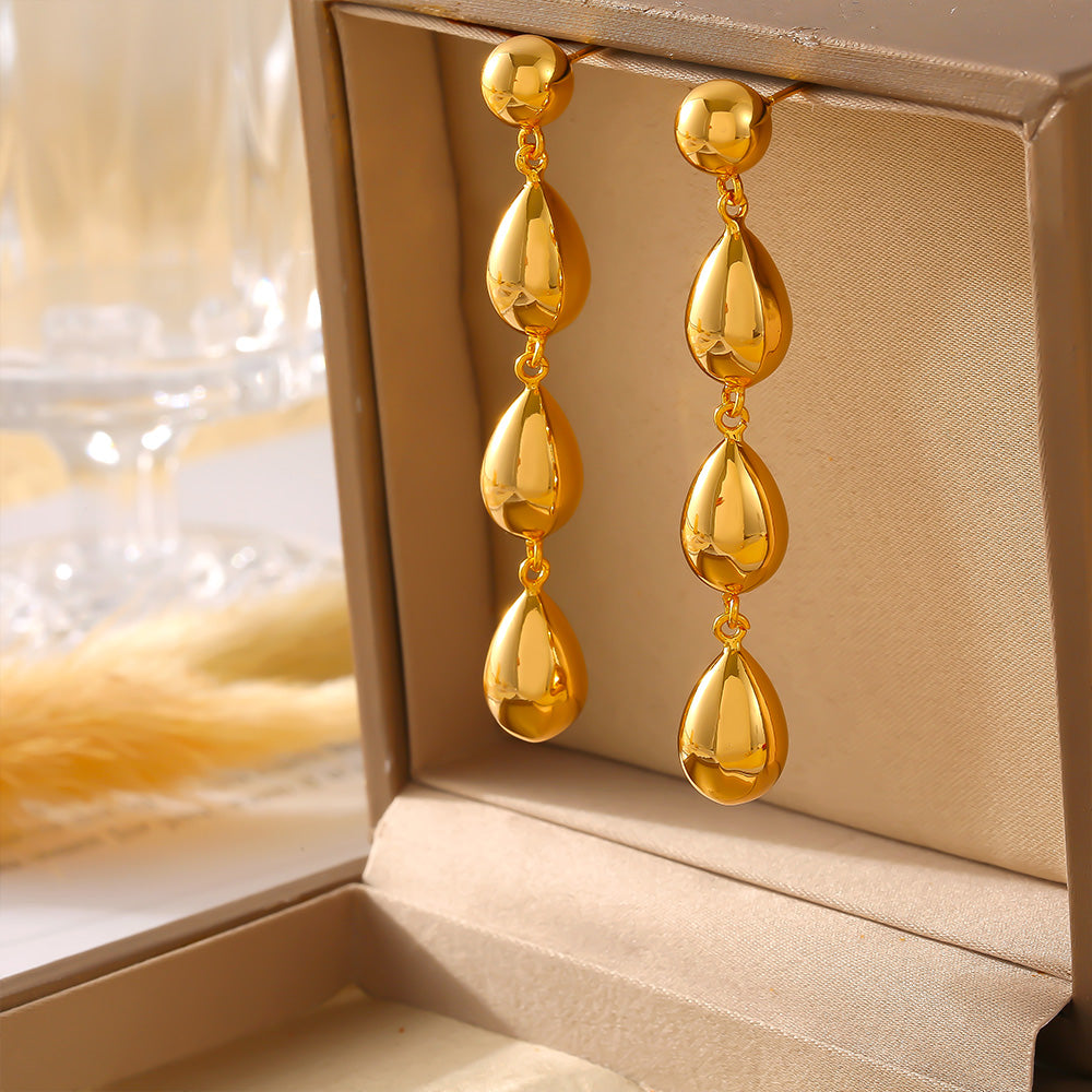 Gold teardrop earrings in an open jewelry box with a blurred background