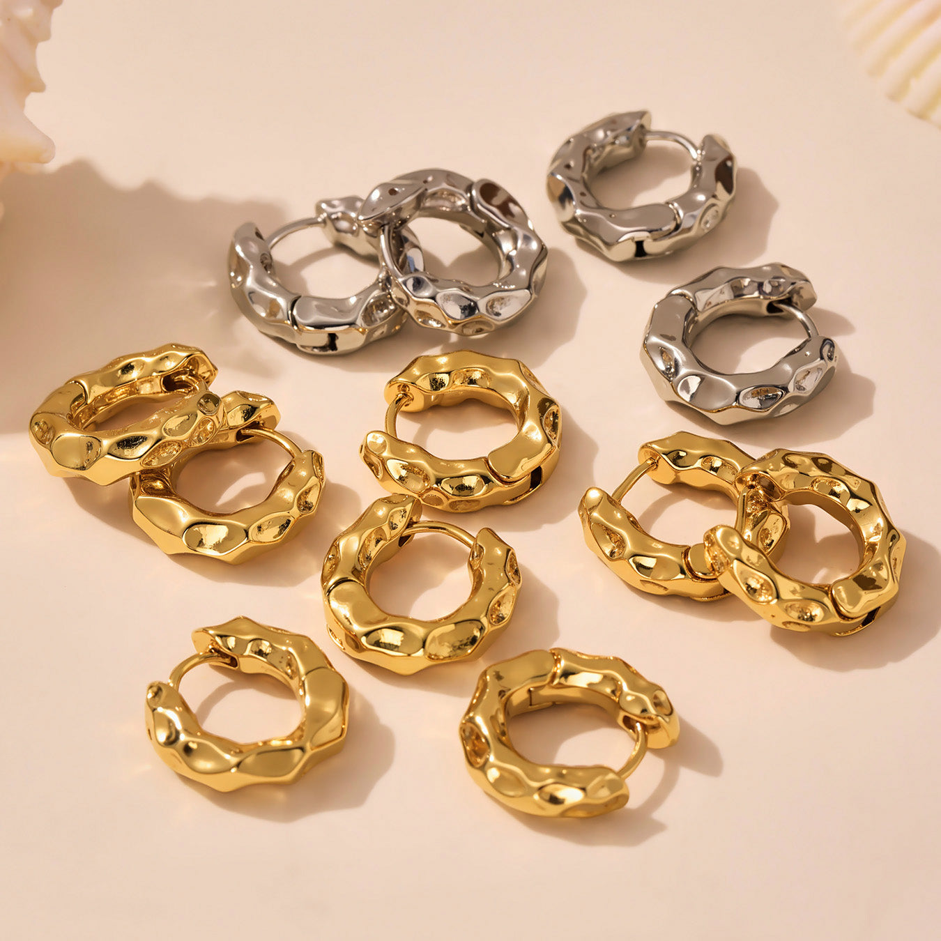 Gold and silver hoop earrings on a beige background