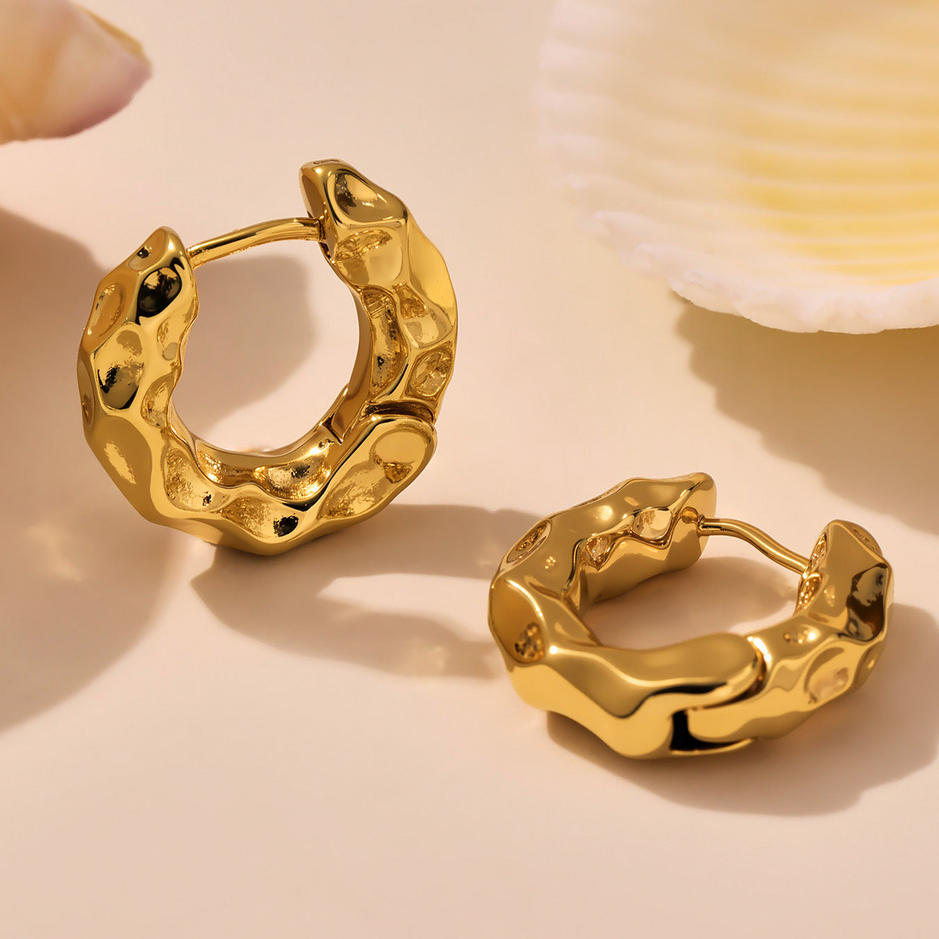 Gold hoop earrings on a beige background