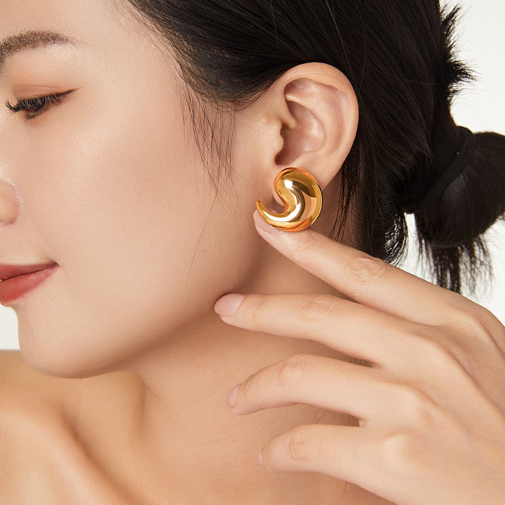 Close-up of a woman wearing a gold spiral earring with a blurred background