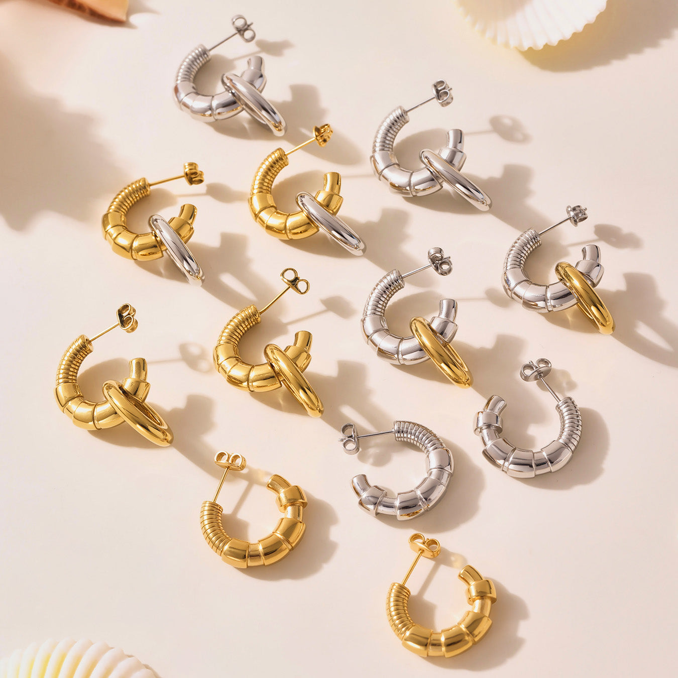 Gold and silver hoop earrings on a beige background