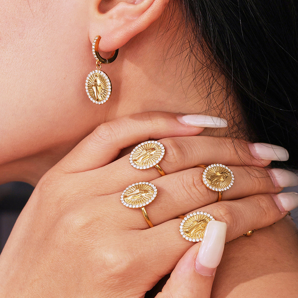 Gold earrings and rings on a person's hand and ear.