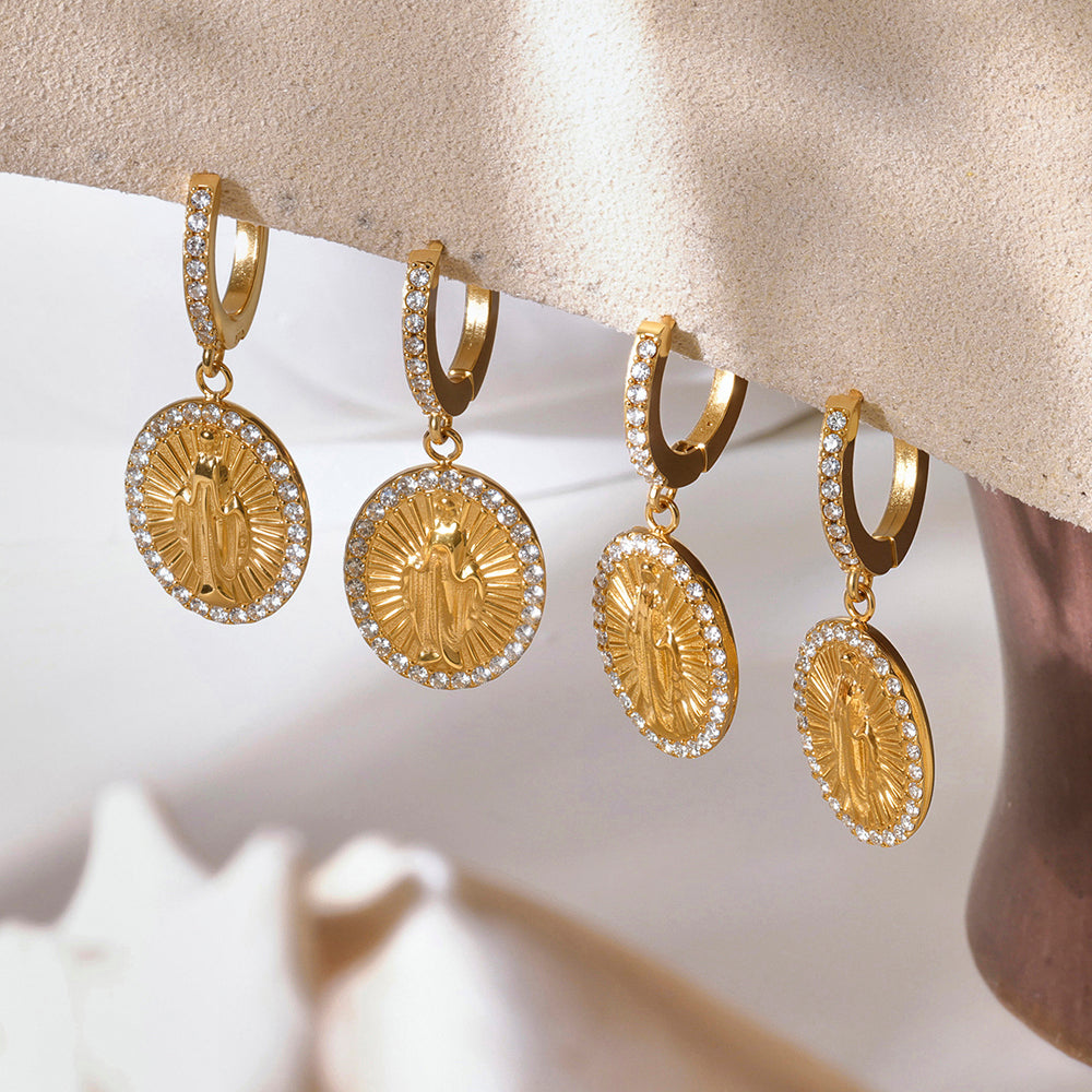 Set of gold earrings with circular designs on a neutral background