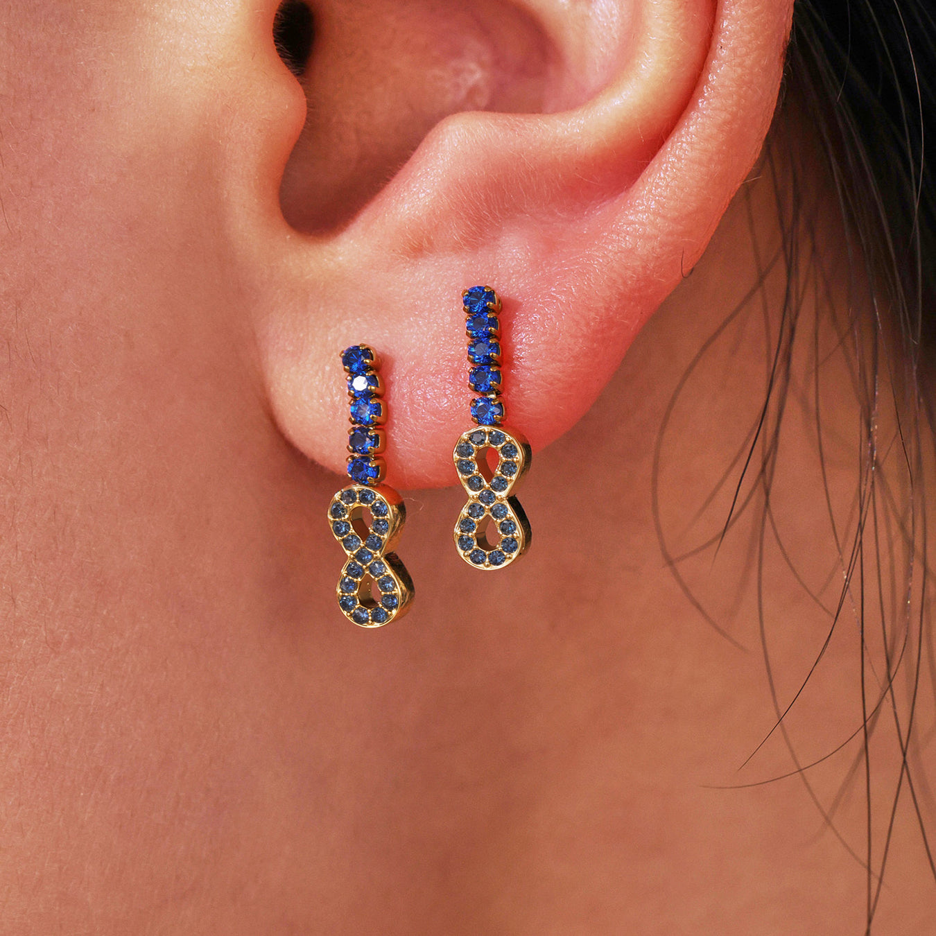 Gold earrings with blue stones worn by a person