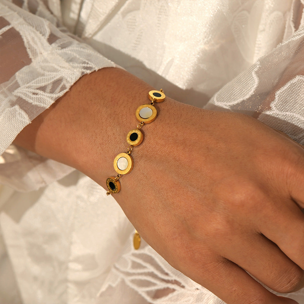 Gold tennis bracelet with round charms styled over white lace fabric