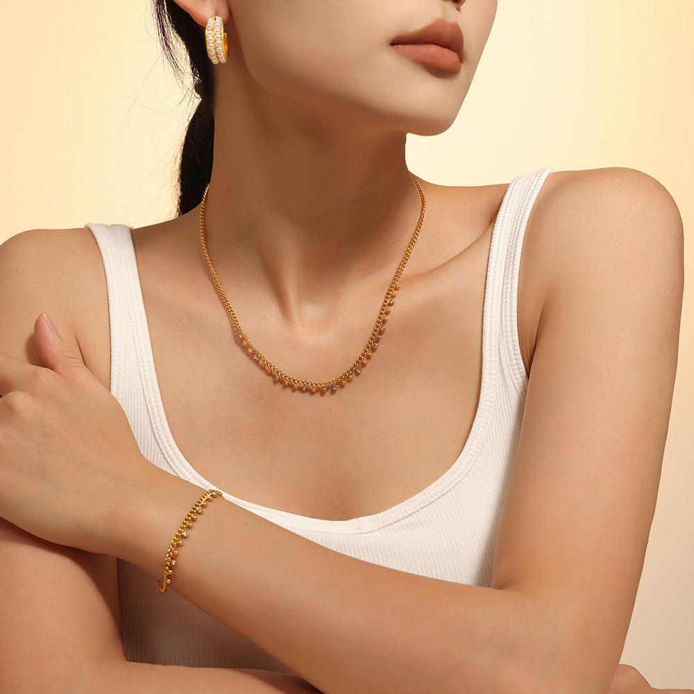 Close-up of model styling waterproof gold bead bracelet and necklace with tassels