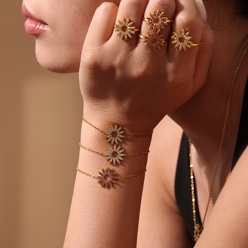 Hand wearing gold floral tennis bracelet and matching rings – close-up view