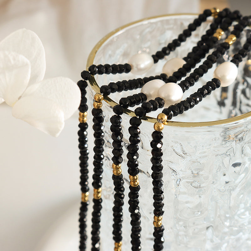 Black pearl necklace styled over ceramic cup