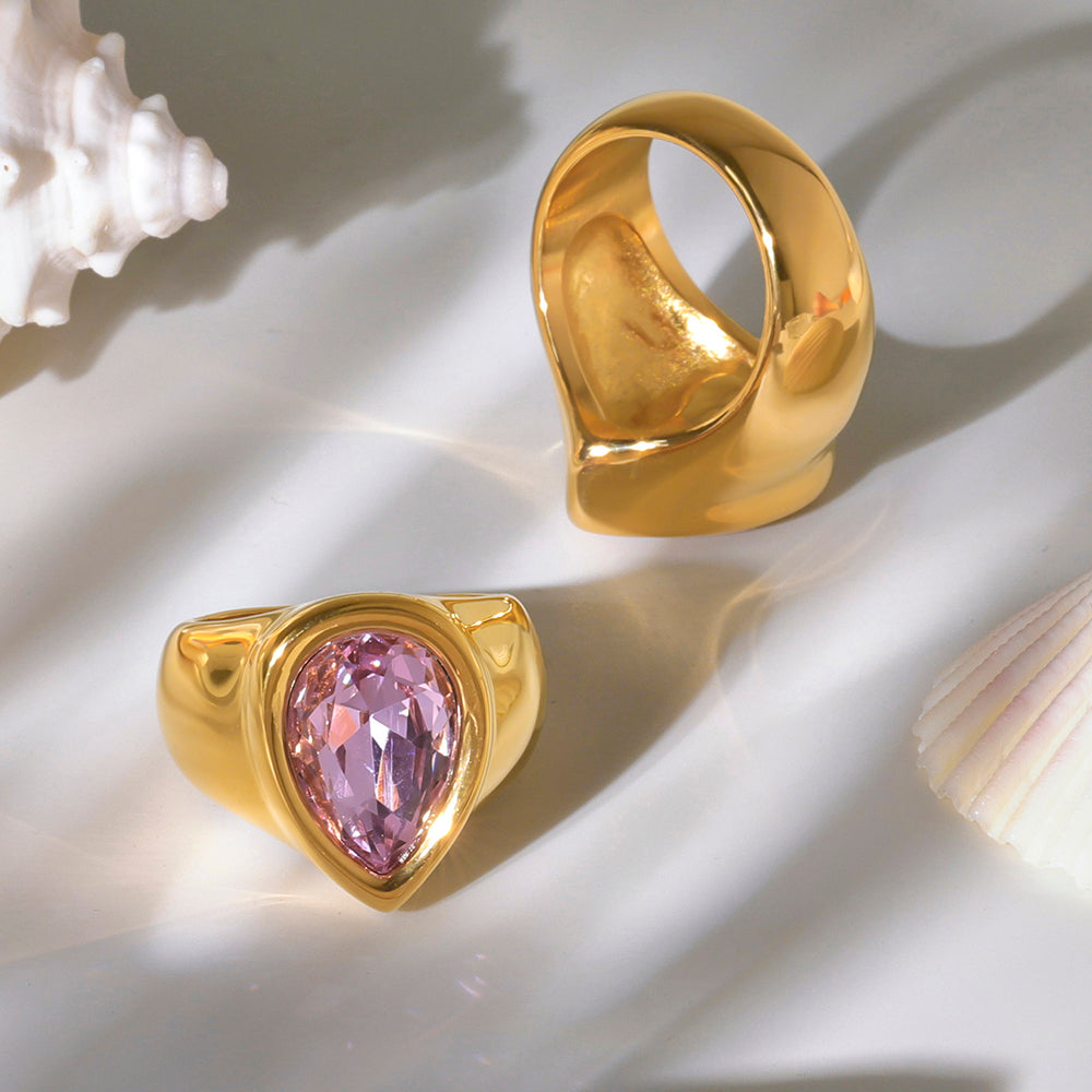 Gold chunky zircon ring featuring a pink gemstone, displayed on a light background.