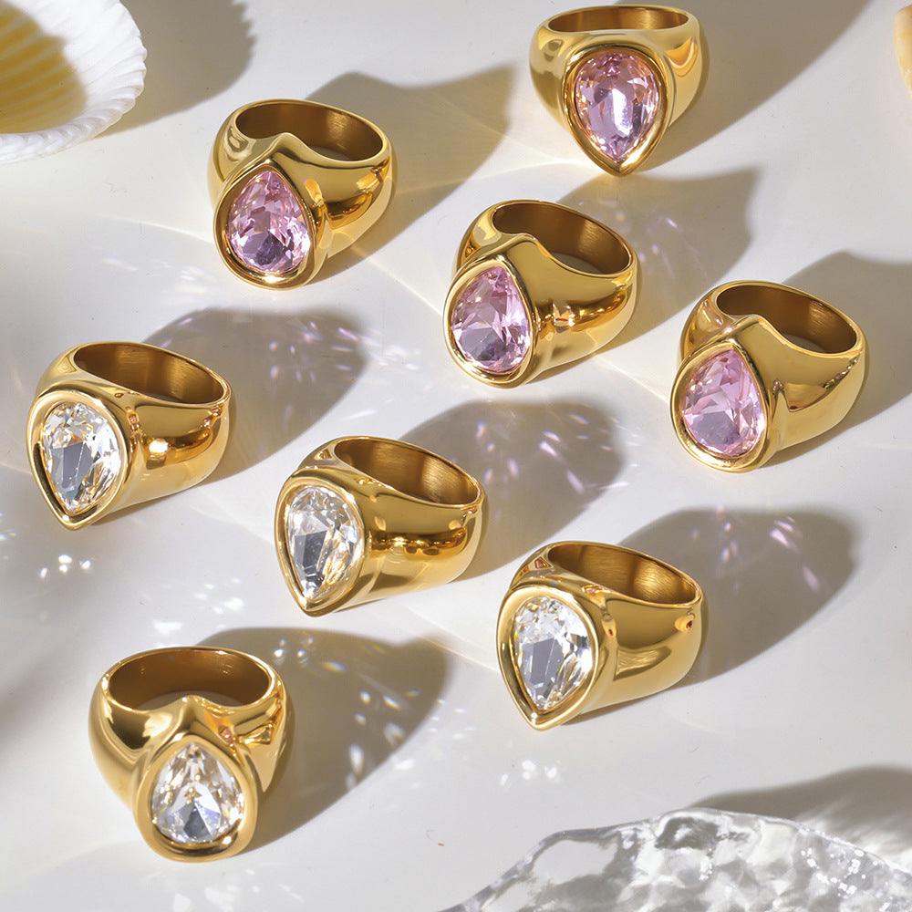 Gold chunky zircon rings featuring pink and clear gemstones displayed on a light background.