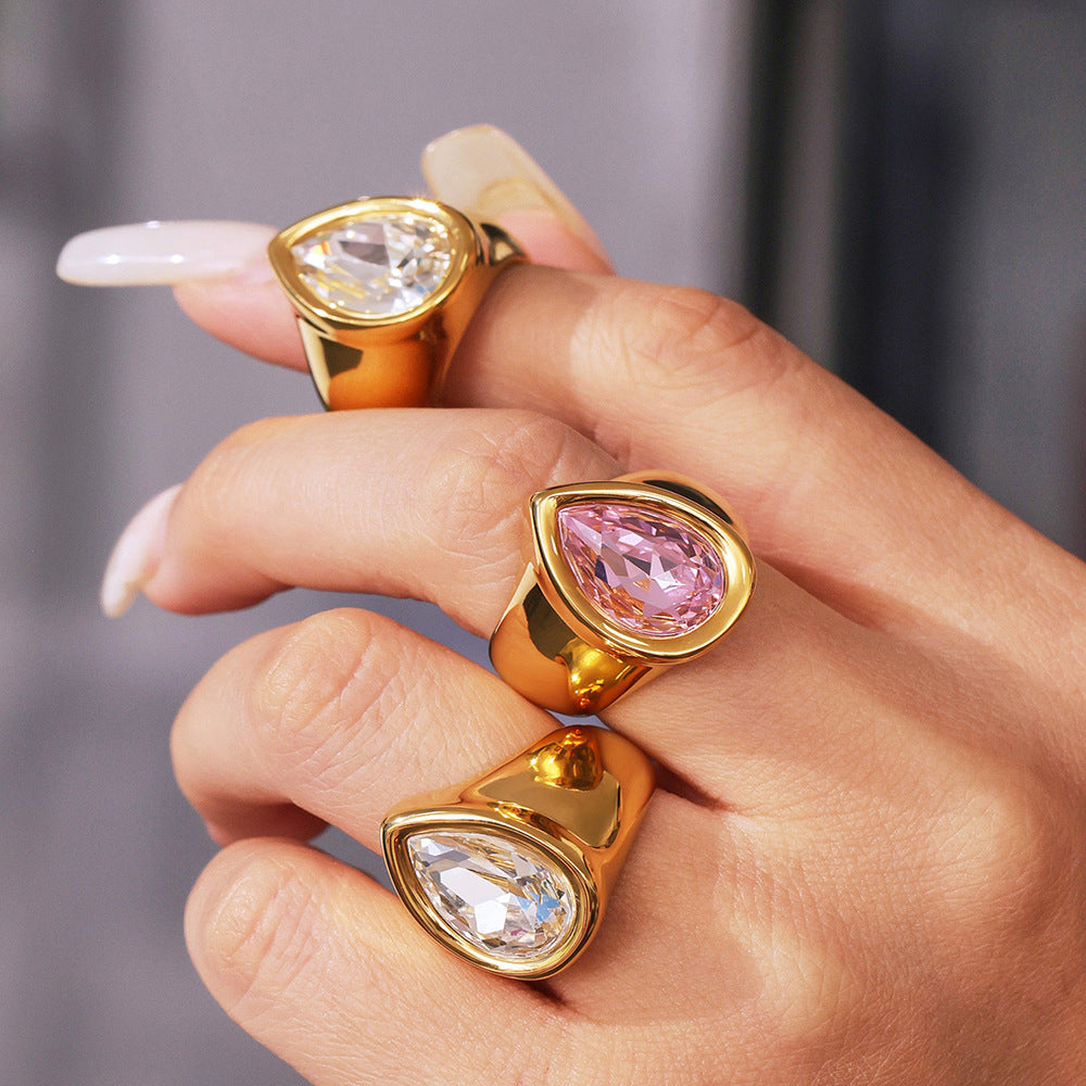 Gold chunky zircon rings featuring teardrop-shaped gemstones, displayed against a blurred background.