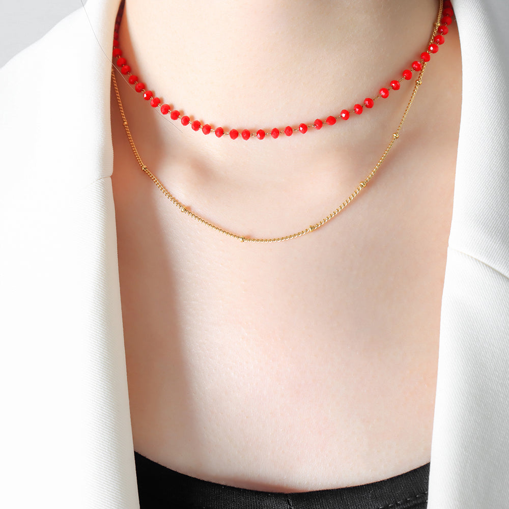 Model wearing layered sea glass necklaces in red and black tones