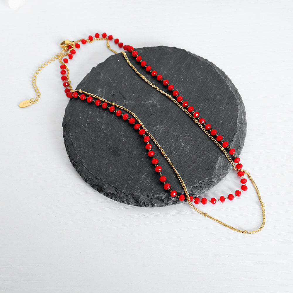 Red sea glass necklace placed on coastal stones for beach styling