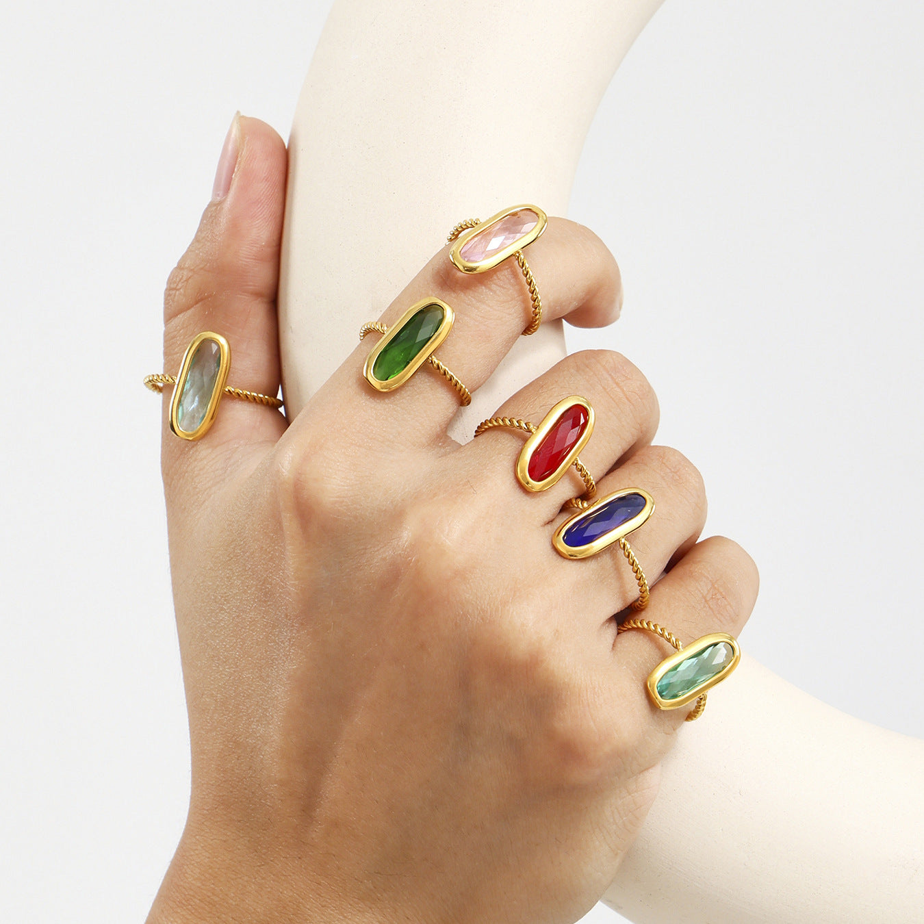 Hand model wearing layered gold sea glass rings with vibrant Czech-style gemstones