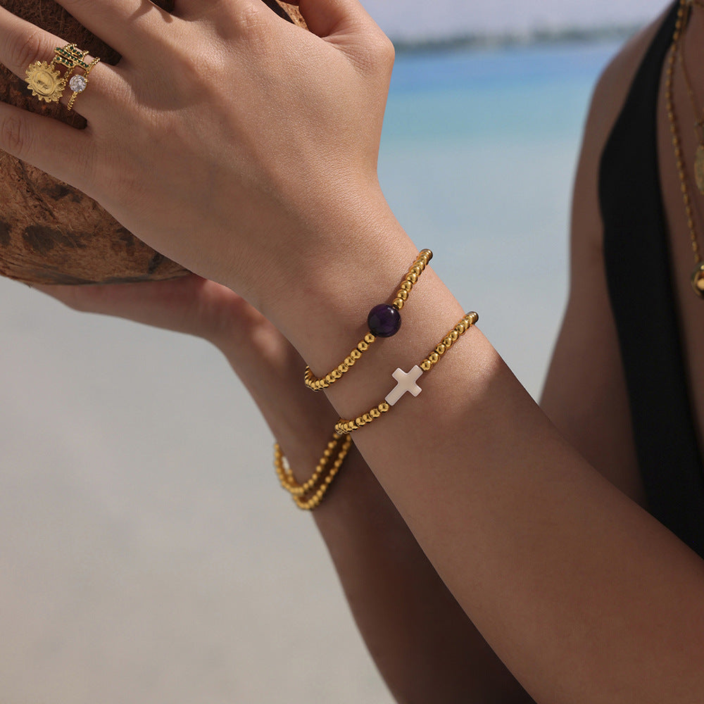 Model Wearing Layered Cross Charm Beaded Bracelets in Gold with Shell and Agate Beads