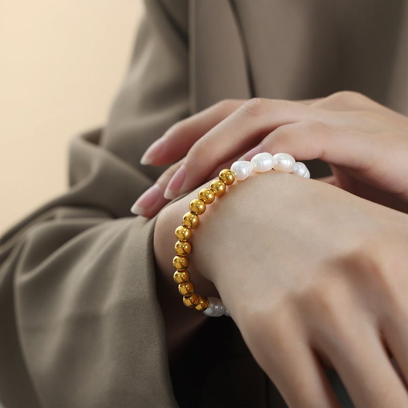 Model wearing handmade freshwater pearl bracelet with dark green suit, full-body view