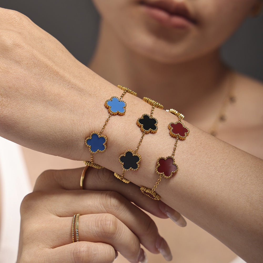 Female model styling gold beaded stainless steel bracelets in black agate, blue agate, and red agate on wrist