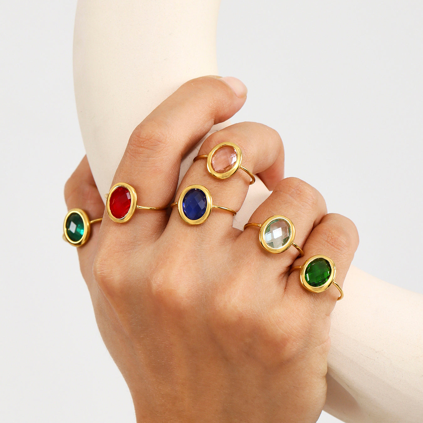 Hand wearing stacked sea glass rings with gold finish and colorful stones