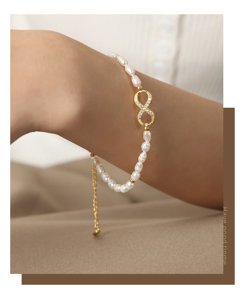 Gold infinity pearl bracelet styled with casual outfit on female model