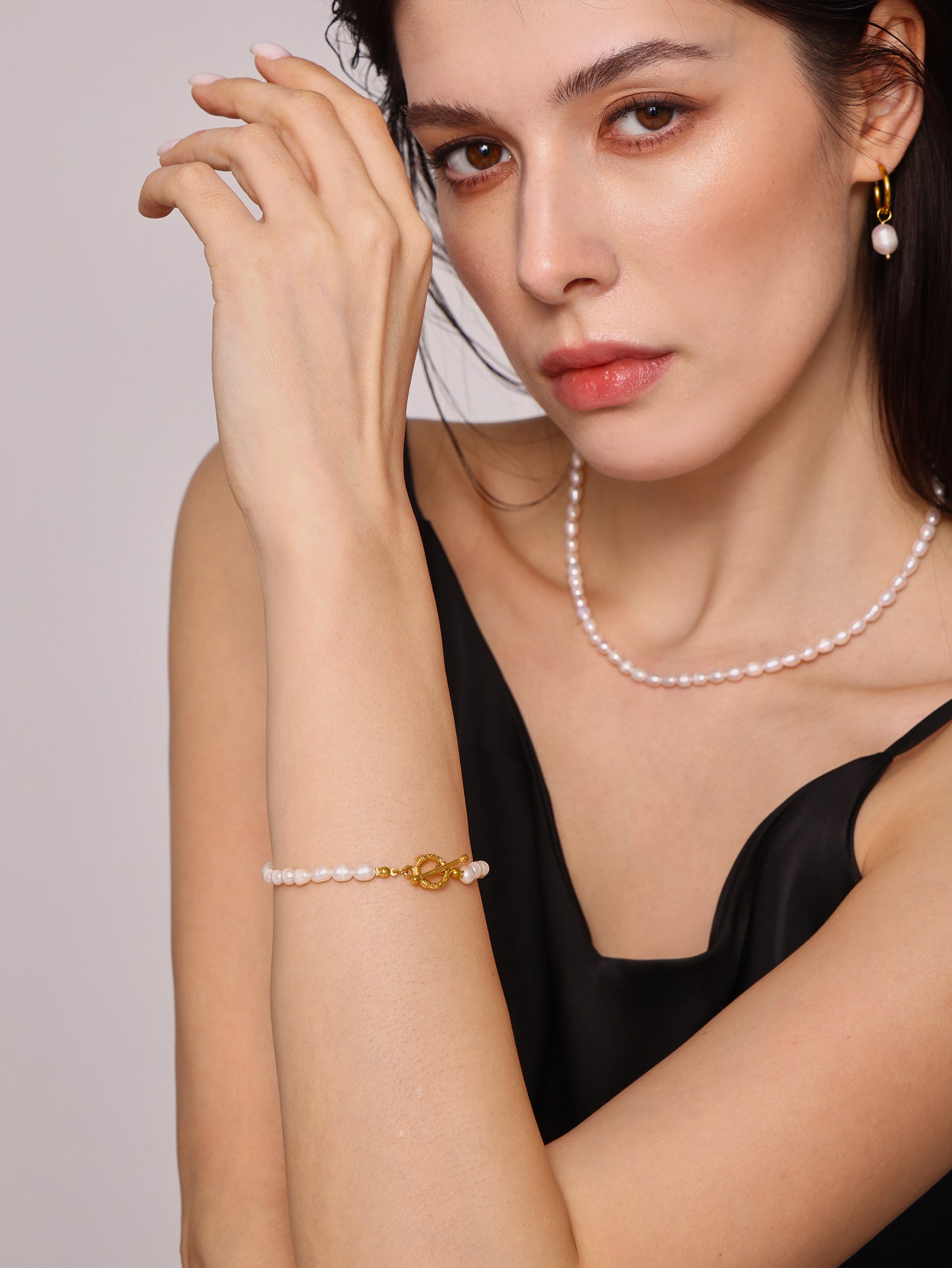 Close-up of model's wrist wearing gold T-bar freshwater pearl bracelet
