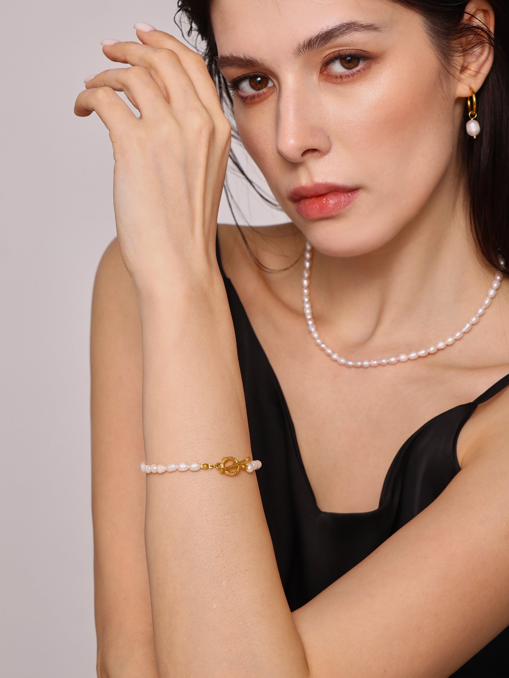 Close-up of model's wrist wearing gold T-bar freshwater pearl bracelet