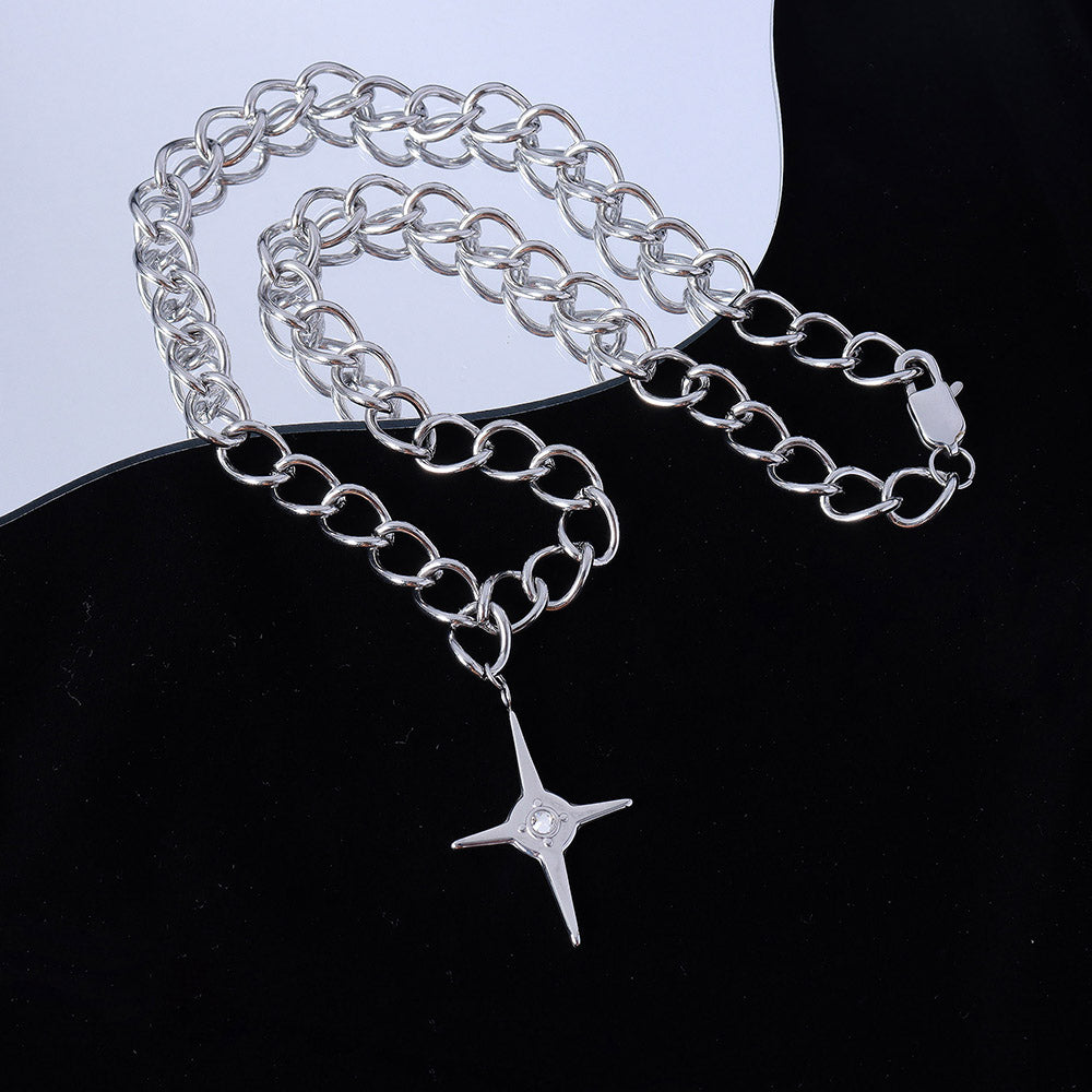 Silver chain necklace with a star-shaped pendant on a black surface