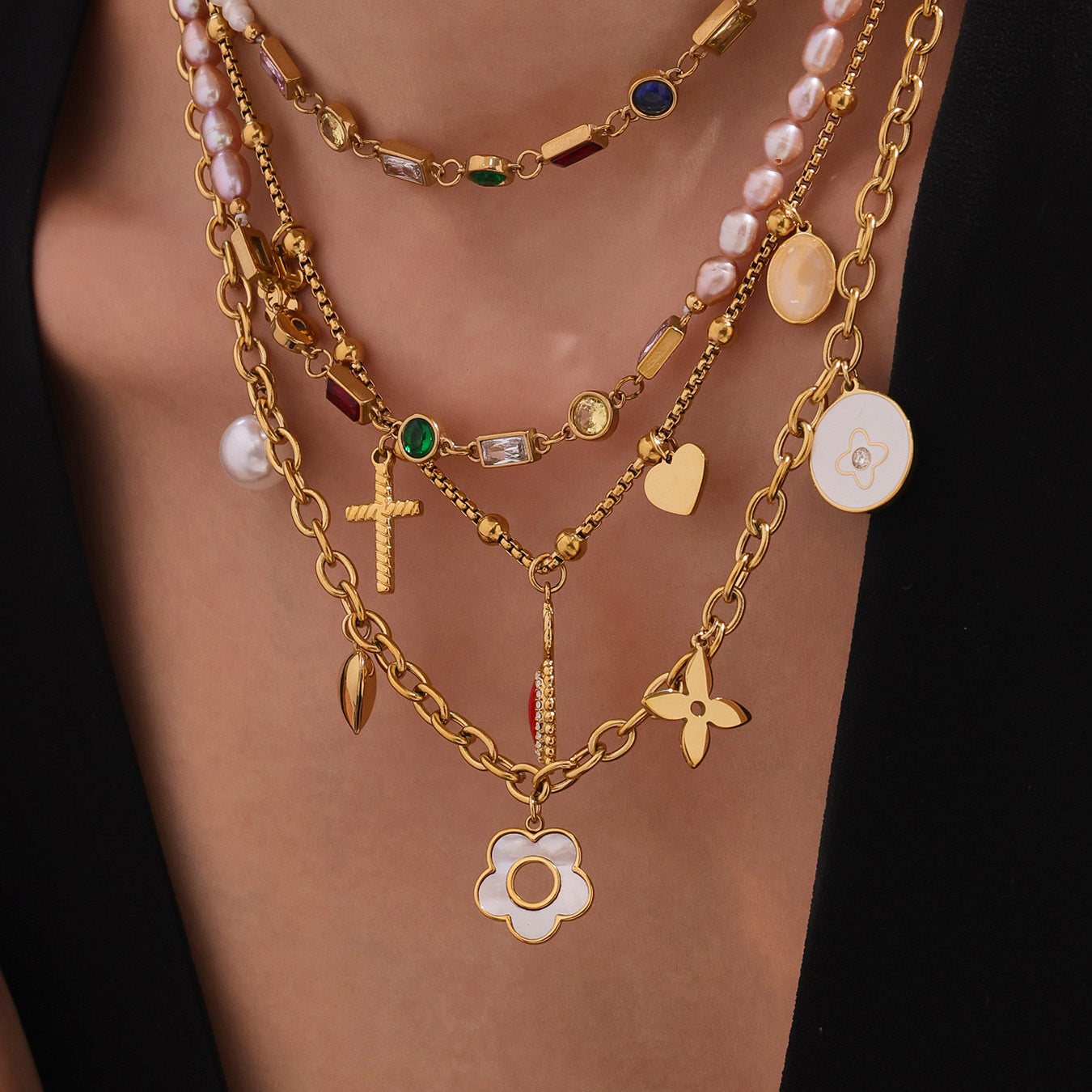 Gold necklaces with various charms on a person's neck against a black background