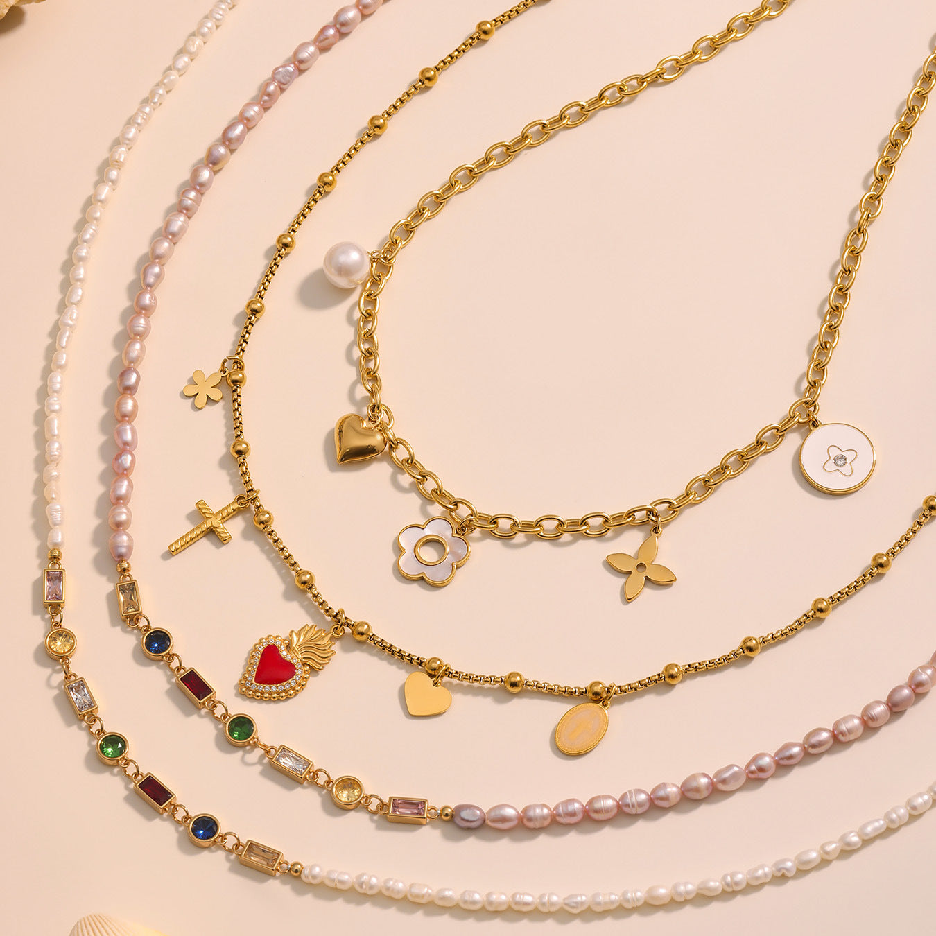 Set of gold and pearl necklaces with various charms on a beige background