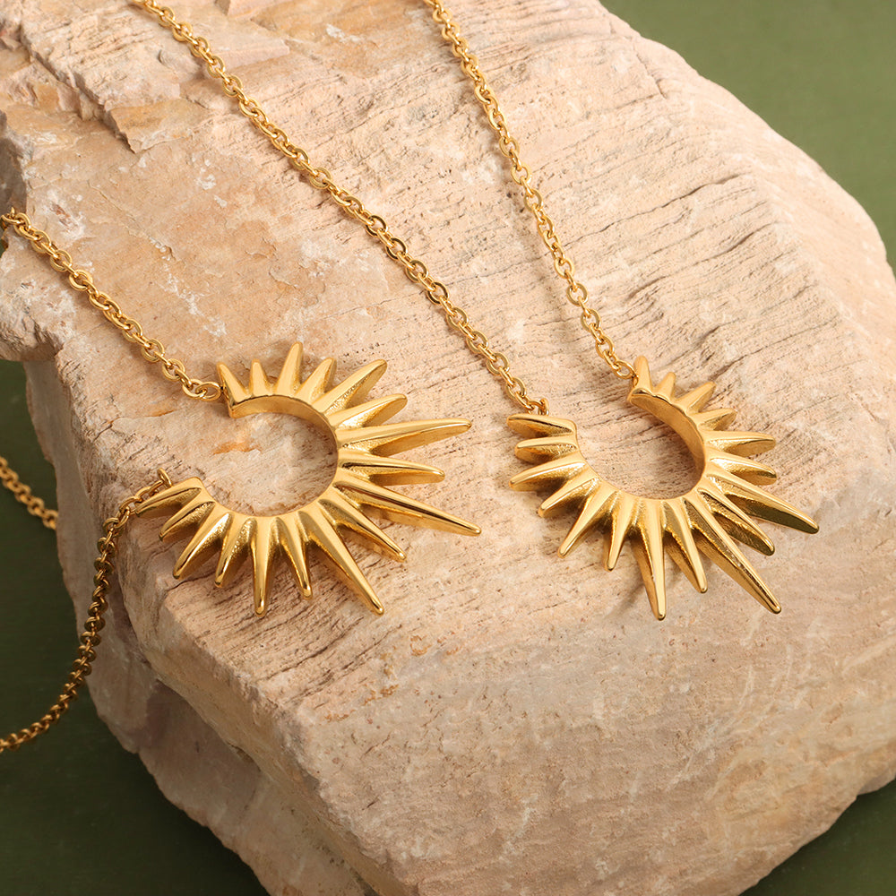 Gold sun and moon pendant necklace on a stone surface