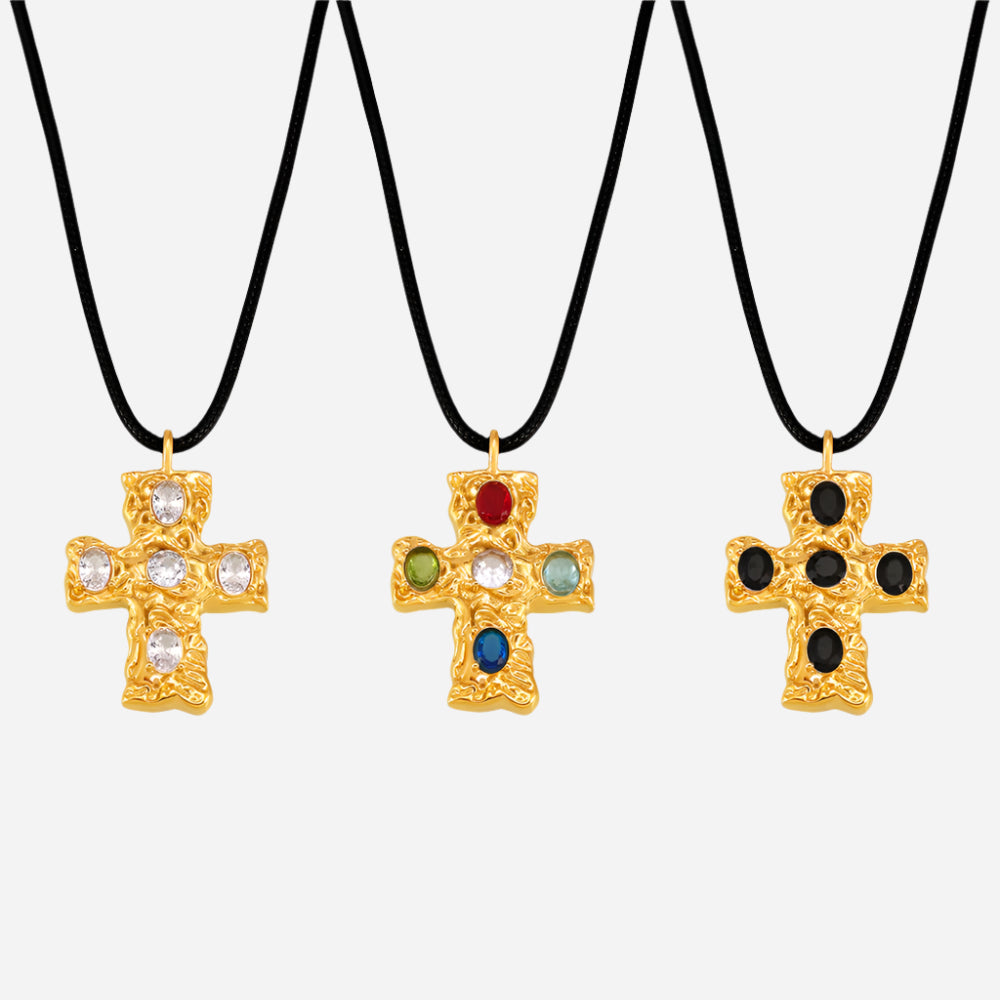 Three gold cross necklaces with colored stones on black cords against a white background