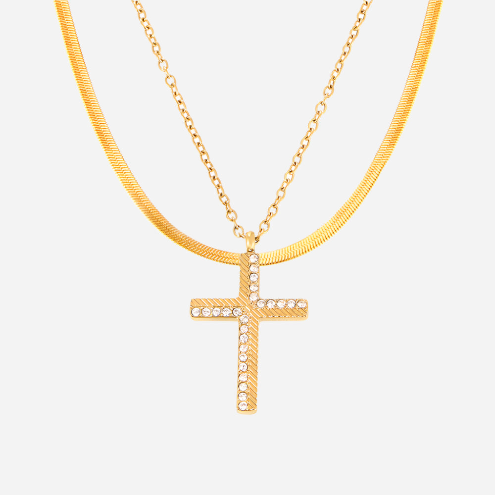 Gold necklace with a cross pendant on a light gray background