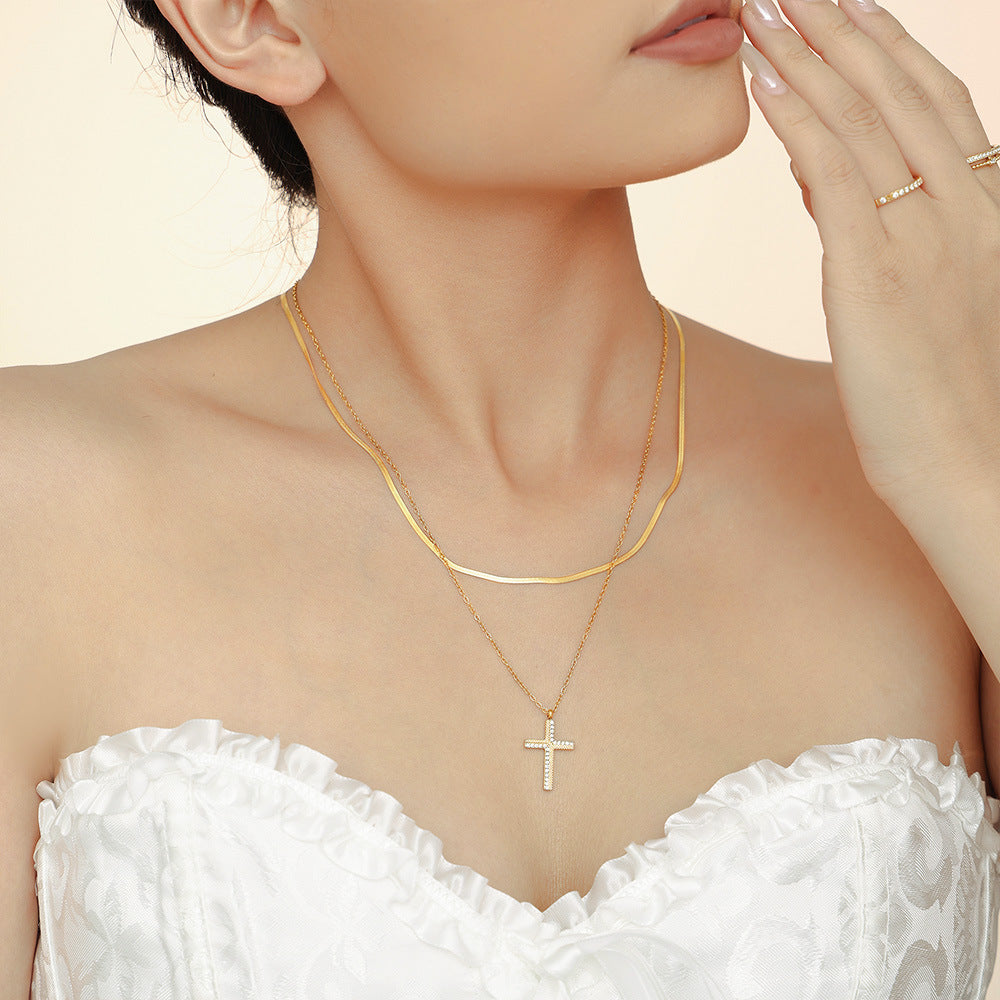Woman wearing a gold necklace with a cross pendant on a beige background