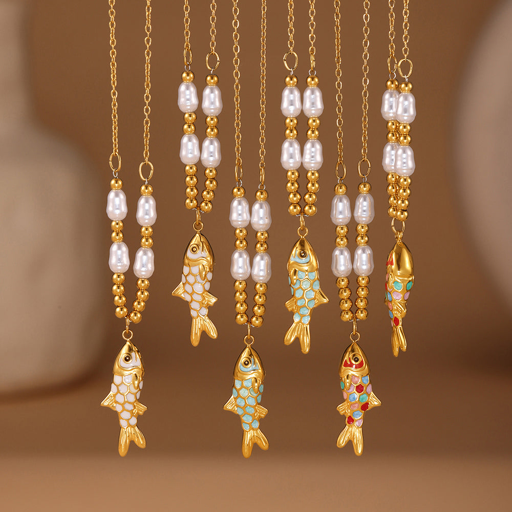 Gold fish-shaped pendants with pearl and gemstone accents on a brown background