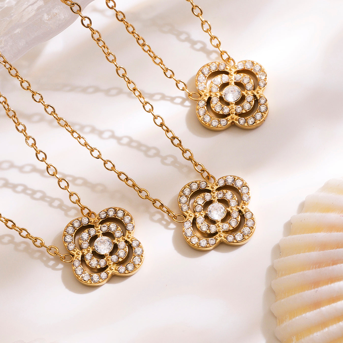 Gold necklaces with floral pendants on a white background