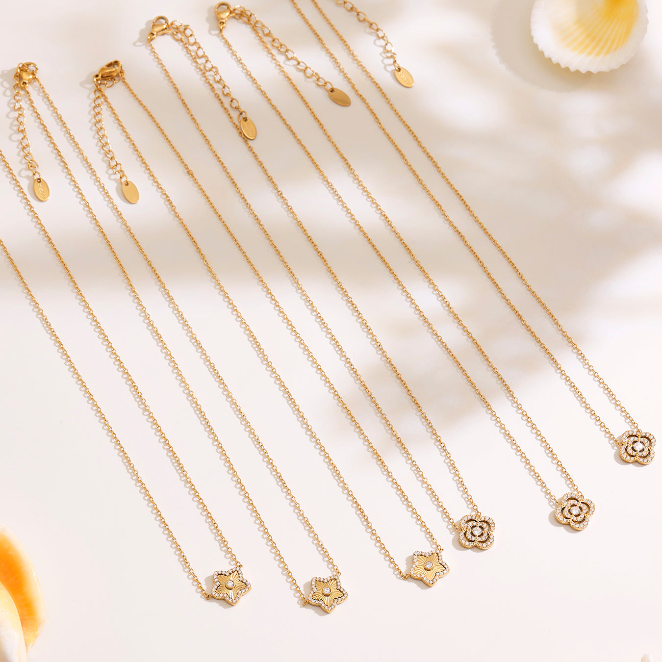 Gold necklaces with floral pendants on a light background