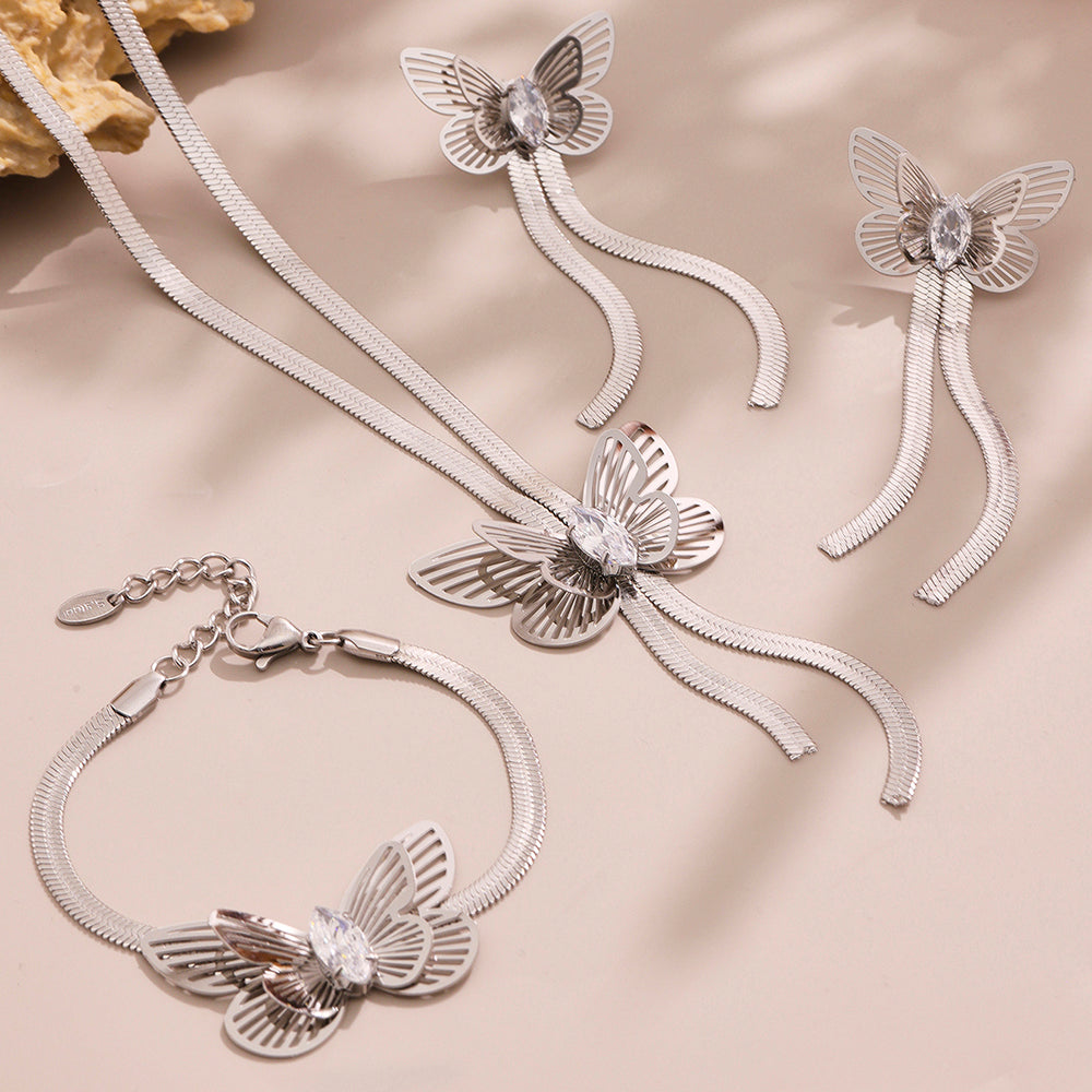 Silver butterfly-themed jewelry set including necklace, bracelet, and earrings on a beige background