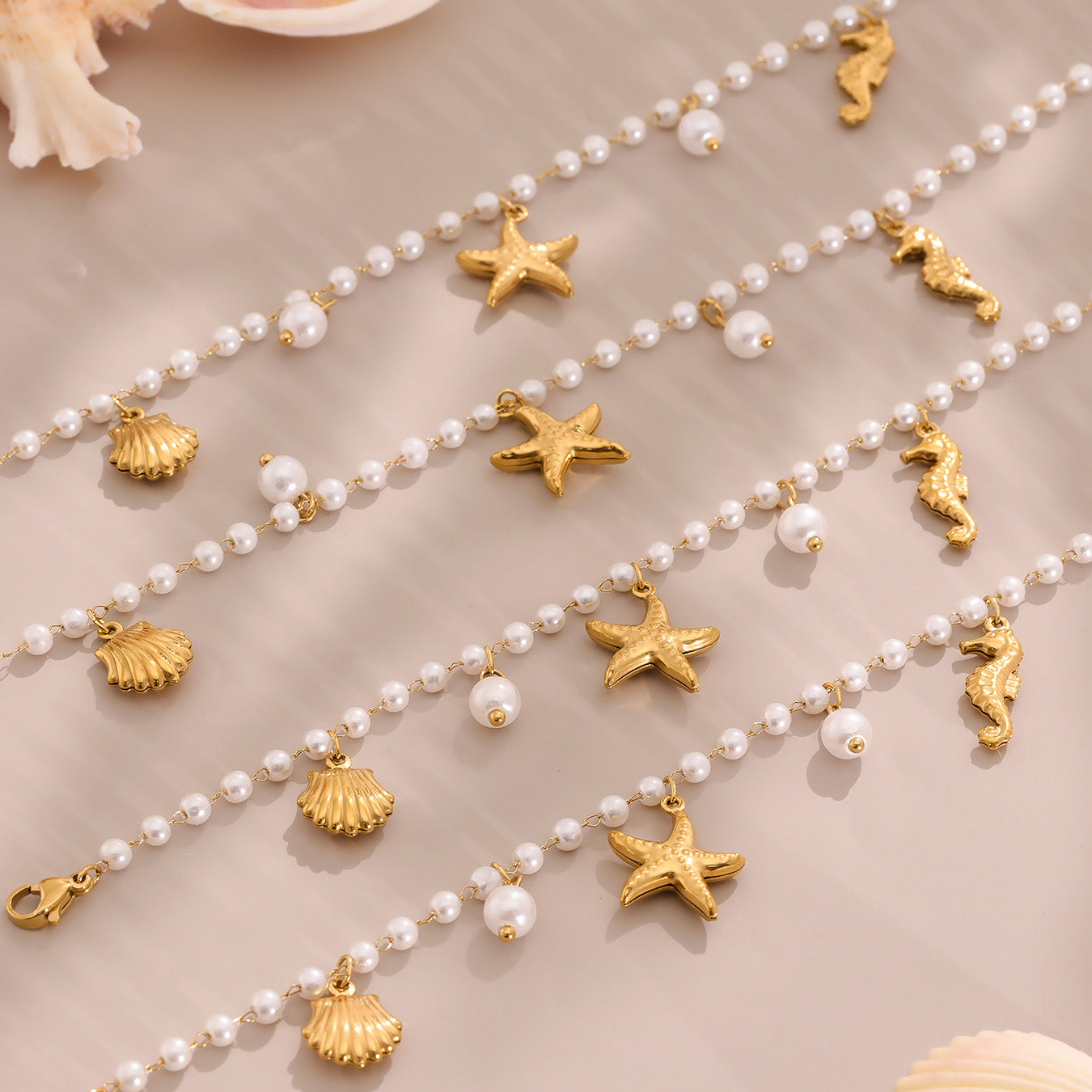 Pearl necklace with gold starfish and shell pendants on a beige background