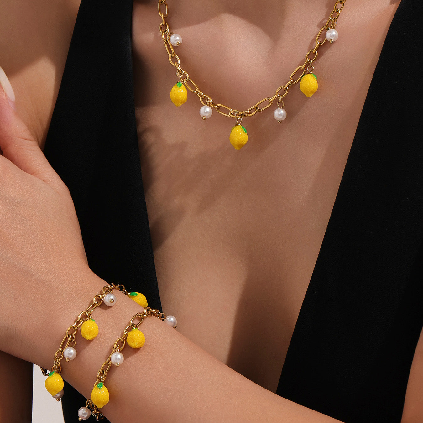 Gold necklace and bracelet with yellow and white beads on a person wearing black.
