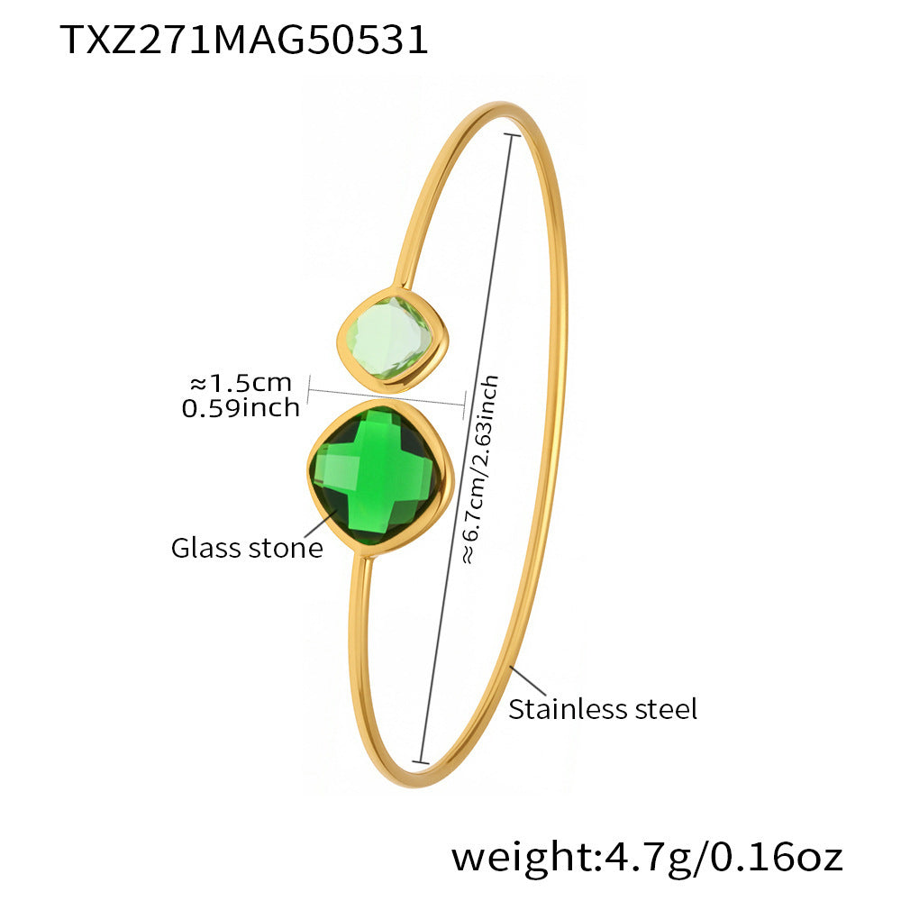 Gold bracelet with green glass stones and measurements on a white background