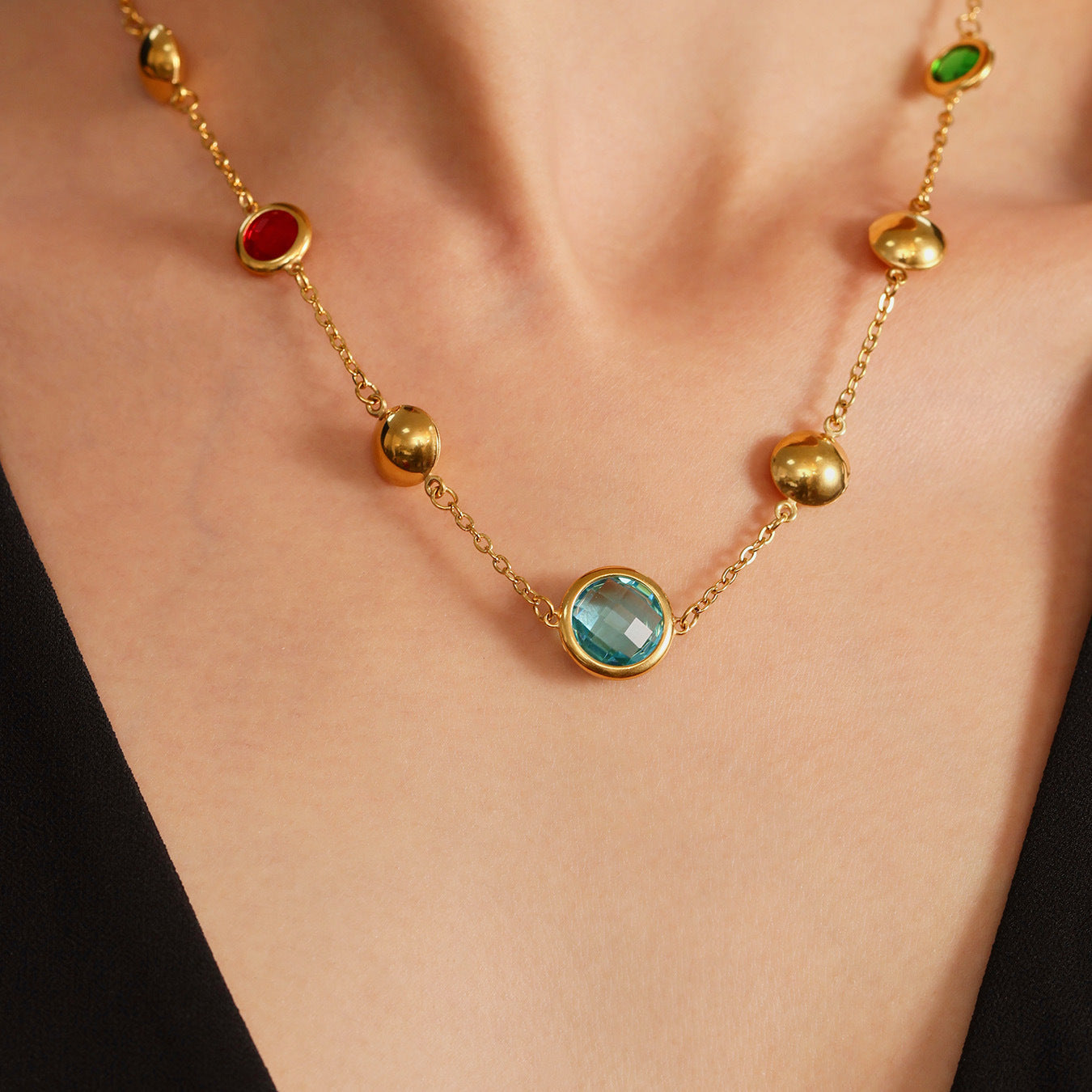 Gold necklace with gemstones on a person wearing a black top