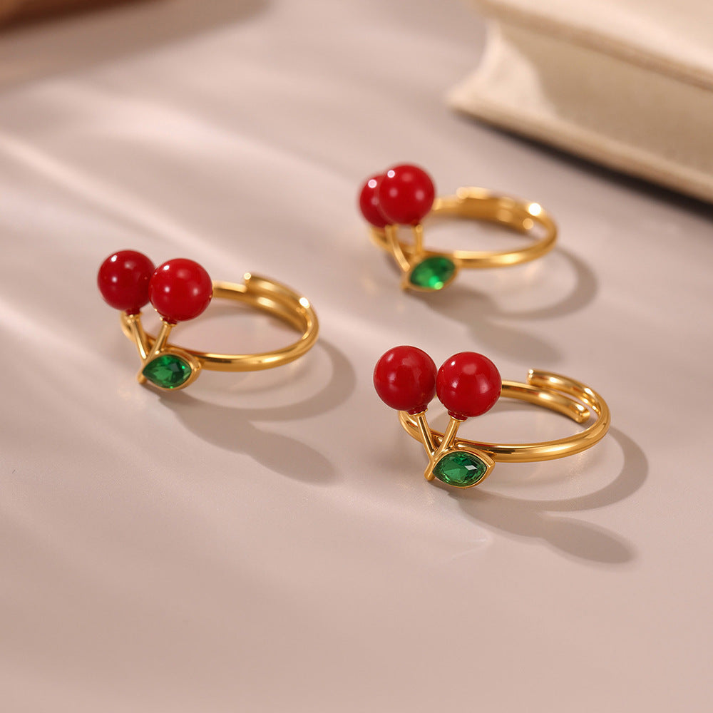 Gold earrings with sea glass-style red and green gemstones on beige
